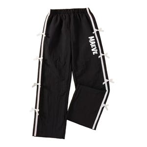 May include: Black wide-leg pants with white side stripes and small white bows. The word "MAEVE" is printed in white on the right leg. The pants have an elastic waistband.