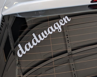 May include: White car with a black roof rack and a white vinyl sticker on the back window that says "dadwagen".