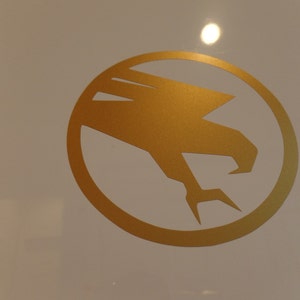 May include: A gold-colored eagle silhouette inside a circle, a graphic design element.