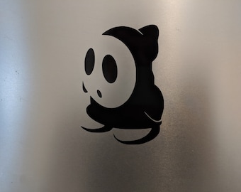 May include: Black and white silhouette of a video game character with a mask and a large, round head.