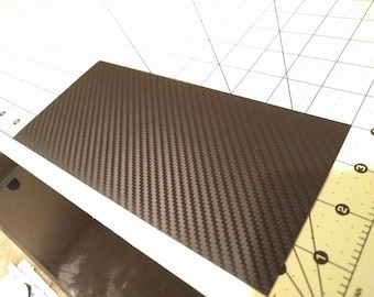 May include: A sheet of black carbon fiber vinyl with a woven pattern.