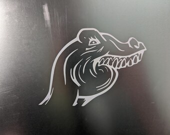 May include: A white silhouette of an alligator's head with an open mouth and sharp teeth. The alligator is facing to the right and has a detailed design.