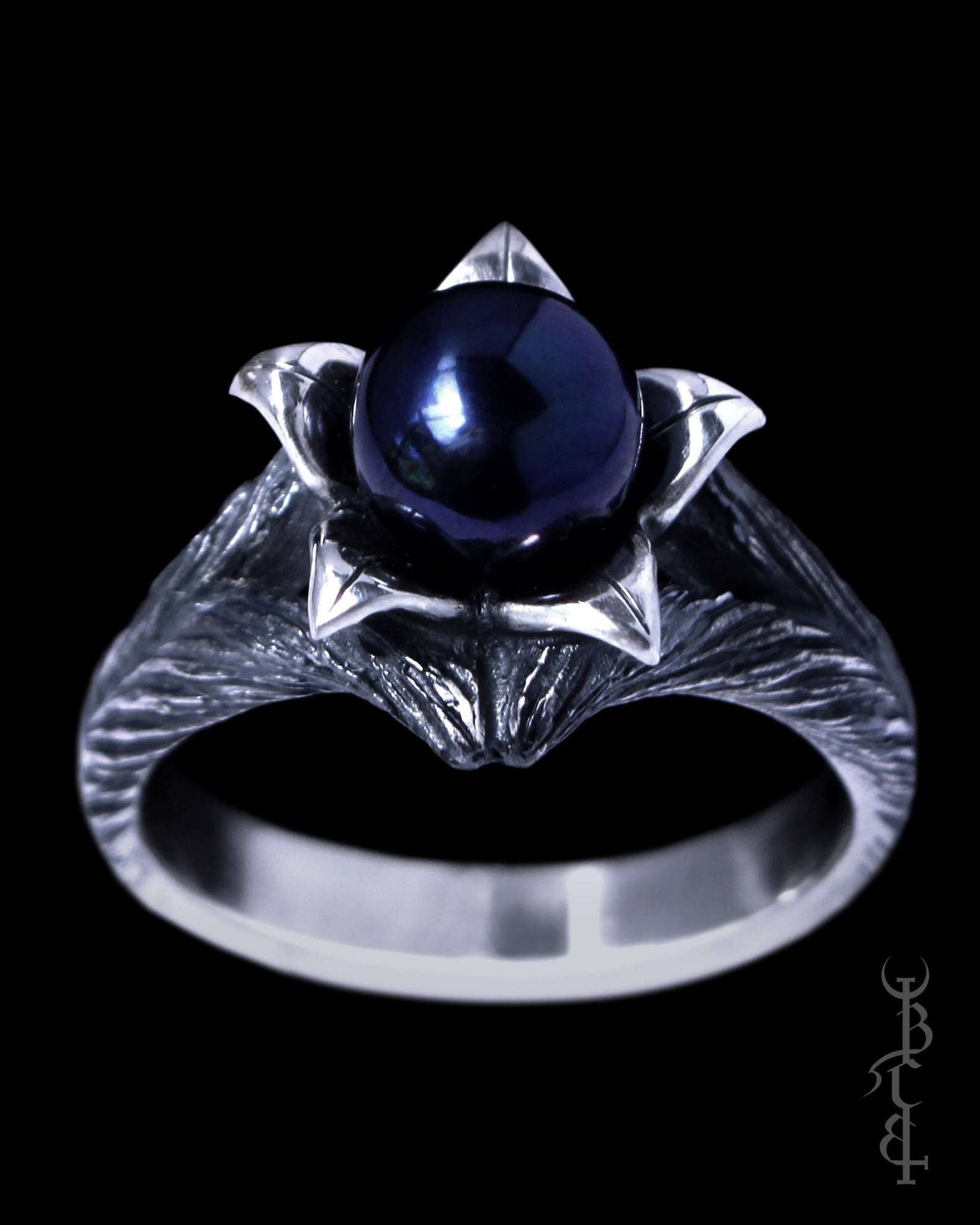 Gothic silver ring with black pearl nestled in pointed leaf petals on textured branch band