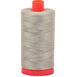 May include: A spool of light gray thread with a red plastic bobbin.