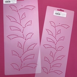 May include: Two clear plastic quilting stencils with a leaf design. The stencils are 9 inches long and feature a repeating pattern of leaves and stems.