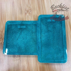 May include: A teal blue, two-piece, resin tray with a glitter finish. The tray has a rectangular shape with a smaller rectangular section attached to the larger section. The smaller section is on the right side of the larger section.