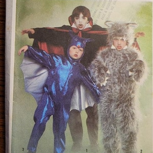 May include: Simplicity sewing pattern number 9206 for boys and girls sizes 2-4. The pattern includes instructions for making three Halloween costumes: a vampire, a bat, and a werewolf. The image shows three children wearing the costumes.