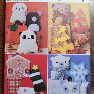 May include: A Simplicity sewing pattern for making plush toys. The pattern includes instructions for making a ghost, a cat, a pumpkin, a panda, a bear, a Christmas tree, a gingerbread house, a Santa Claus, a polar bear, a snowflake, and an owl. The pattern is for one size.