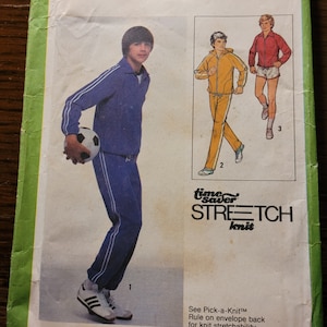 May include: Simplicity sewing pattern number 8808 for a teen boy's tracksuit. The pattern includes instructions for a blue and white tracksuit with a zippered jacket and matching pants. The pattern is for sizes 14, 16, and 18.