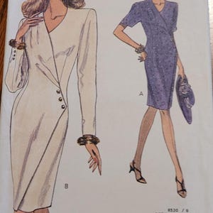 May include: Very Easy Very Vogue sewing pattern. The pattern features illustrations of two dresses: a white, long-sleeved dress with button details and a purple, short-sleeved wrap dress. The pattern size is 8-10.