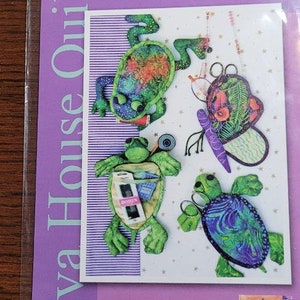 May include: A pattern for making 8-inch glasses and notions cases. The pattern features a frog, a butterfly, and two turtles. The pattern is titled "Just In Cases" and is by Java House Quilts.