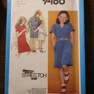 May include: Simplicity sewing pattern number 9486 for a girl's dress. The pattern is for sizes 10, 12, and 14. The pattern includes instructions for making a blue dress with a V-neck and short sleeves.