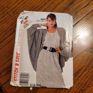 May include: A vintage McCall's sewing pattern titled "Stitch 'N Save." The pattern features a woman wearing a dress and jacket with a black and white spotted design. The pattern size is A (10-12-14).