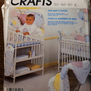 May include: A vintage McCall's Crafts pattern envelope featuring a baby's room theme. The cover displays a crib, changing table, and baby items. Text includes "For Baby's Room" and instructions for making a wall hanging, quilt, pillow cover, and more.