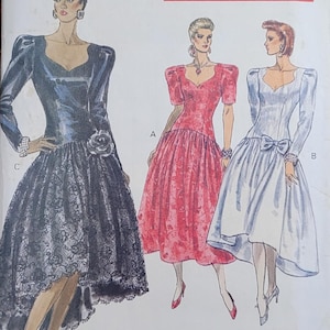 May include: A vintage Vogue sewing pattern for a dress. The pattern includes three different styles: a black dress with a lace overlay, a red dress with puffed sleeves, and a white dress with a bow at the waist. The pattern is labeled "Advanced/Plus Difficile" and is for sizes 6-8-10.