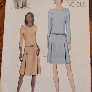 May include: A sewing pattern titled "7542" from Very Easy Vogue, featuring illustrations of two dresses. The pattern includes sizes 20, 22, and 24. One dress is light blue, the other is tan, both with belts and pleated skirts.
