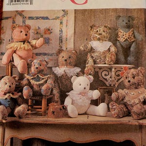 May include: A Simplicity Crafts sewing pattern envelope, number 9594, featuring illustrations of eight distinct teddy bears. The bears are crafted from various patterned fabrics, including floral and plaid prints, and are adorned with lace collars and bows.