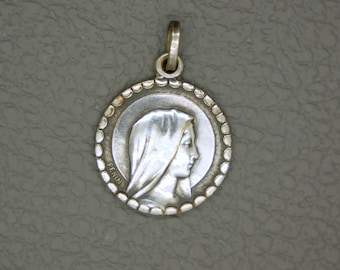 May include: Silver pendant featuring a profile of the Virgin Mary with the word "Pennin" inscribed on the side.