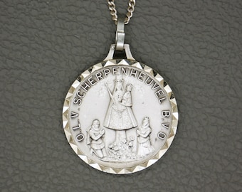 May include: Silver pendant necklace with a round medal featuring a religious image of the Virgin Mary with two figures kneeling before her. The medal is inscribed with the text "O.L.V. SCHERPENHEUVEL B.V.O."