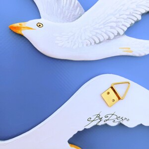 Front and back of handmade wooden seagulls – signed by artist with hanging hook visible - handcrafted coastal wall art