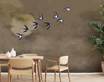 Op de afbeelding: Een eetkamer met een bruine muur met een zwerm gestileerde blauwe en witte zwaluwen die in een cirkel vliegen. De kamer heeft een houten tafel met vier gevlochten stoelen en twee keramische vazen op de tafel.