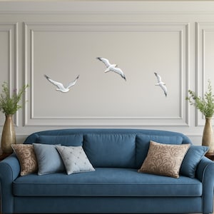 Large coastal wall art with flock of hand painted wooden seagulls above blue sofa