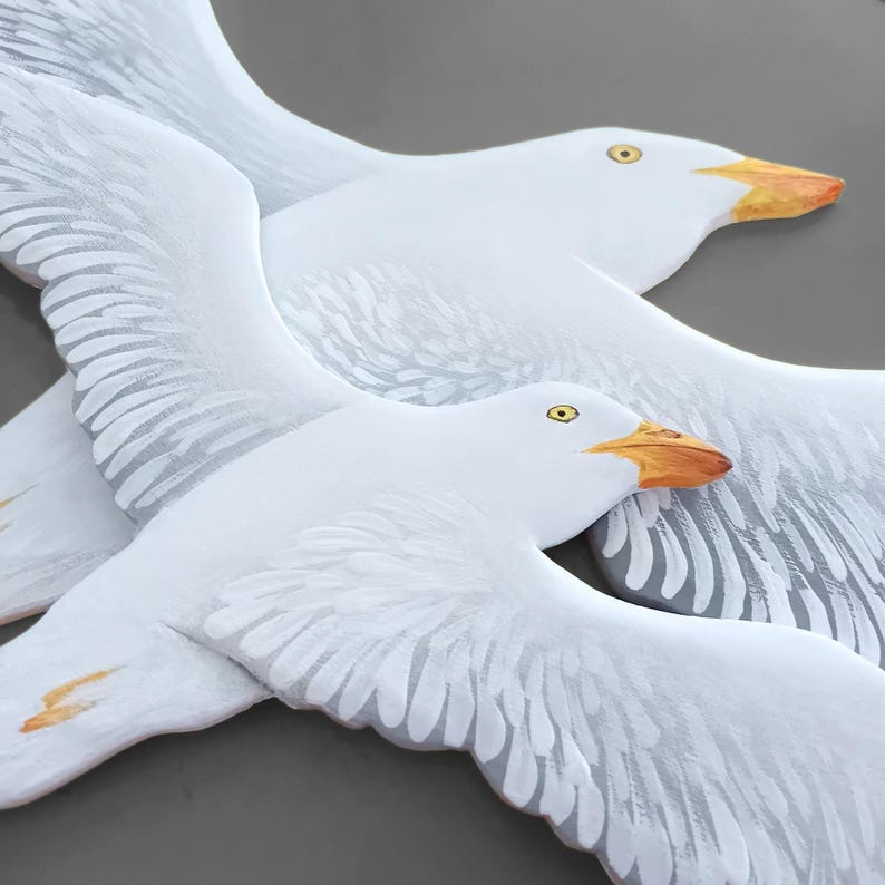 Two hand painted wooden seagulls forming a coastal wall art set