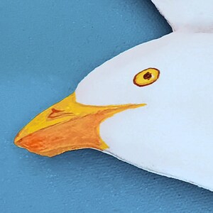 Detail of handmade wooden seagull showing orange beak and white paint finish
