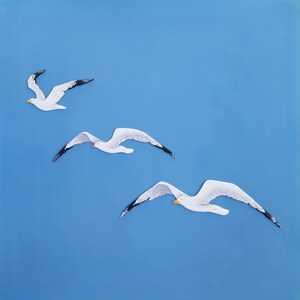 Set of three hand-painted wooden seagulls in flight, white color on blue background – coastal nautical wall art for beach home  decor.