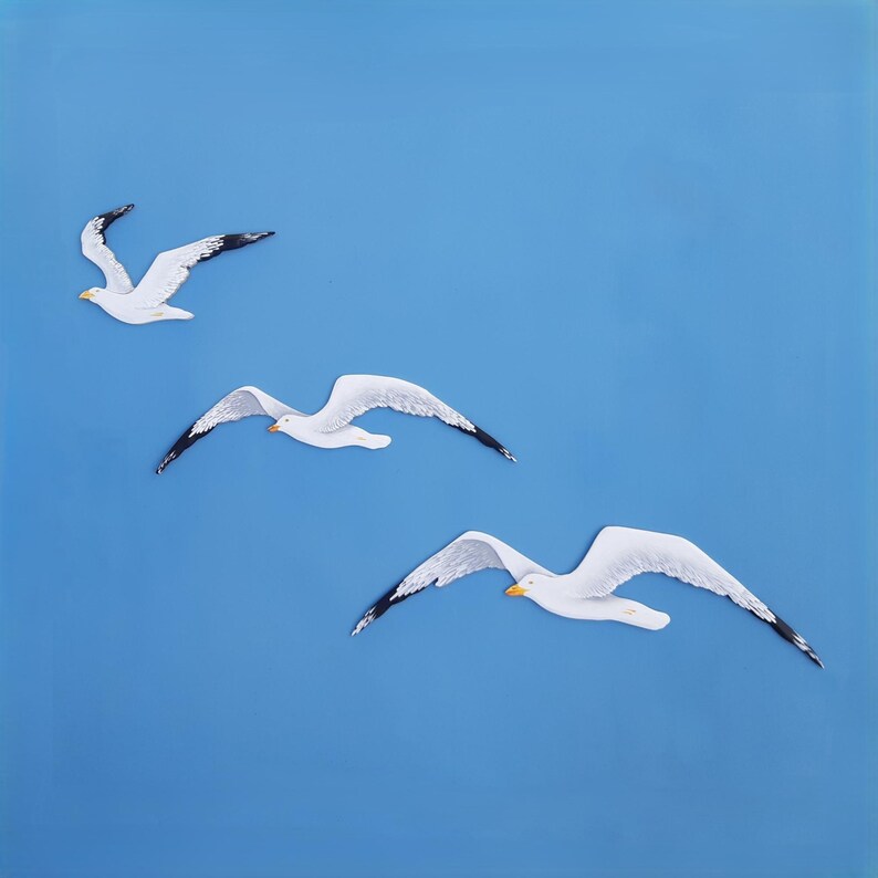 Set of three hand-painted wooden seagulls in flight, white color on blue background – coastal nautical wall art for beach home  decor.