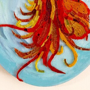 May include: A close-up of a mosaic artwork featuring a red, orange, and yellow design. The mosaic is set against a blue background.