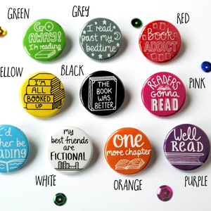 May include: Ten round button pins with various book-themed sayings. The buttons are in different colors, including green, grey, black, red, pink, blue, white, orange, and purple.