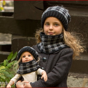 May include: A girl wearing a black and white checkered knit hat and matching neck warmer holds a doll wearing a similar hat and neck warmer. The doll is wearing a white shirt and has blonde hair.