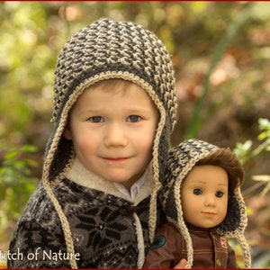 Peut inclure: Un jeune garçon portant un bonnet en tricot gris et blanc avec des rabats d'oreilles tient une poupée portant un bonnet similaire. Le garçon sourit et regarde la caméra. L'arrière-plan est flou et semble être une forêt.