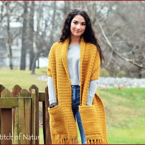 May include: A mustard yellow crochet scarf with a large pocket and fringe. The scarf is worn by a person with long brown hair.