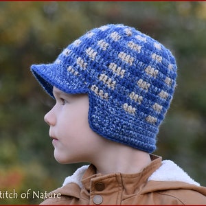 May include: A blue and beige crocheted hat with ear flaps and a brim. The hat has a checkered pattern.