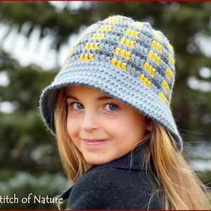 May include: A young person wearing a blue and yellow crocheted bucket hat. The hat has a geometric pattern.