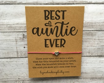 May include: A brown card with the text "BEST auntie EVER" and a pink string bracelet with a silver heart charm. The card also includes instructions for making a wish with the bracelet: "Close your eyes and make a wish, then tie this bracelet on your wrist. When the bracelet breaks in two, the wish you made will soon come true." The card also includes the website layeredandsimple.etsy.com.