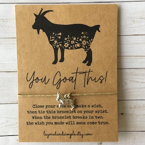 Op de afbeelding: Een bruine kaart met een zwart geit silhouet gevuld met bloemmotieven. De tekst "You Goat This!" staat boven een zilveren geitenbedelarmband. De kaart bevat instructies en de Etsy shop URL.