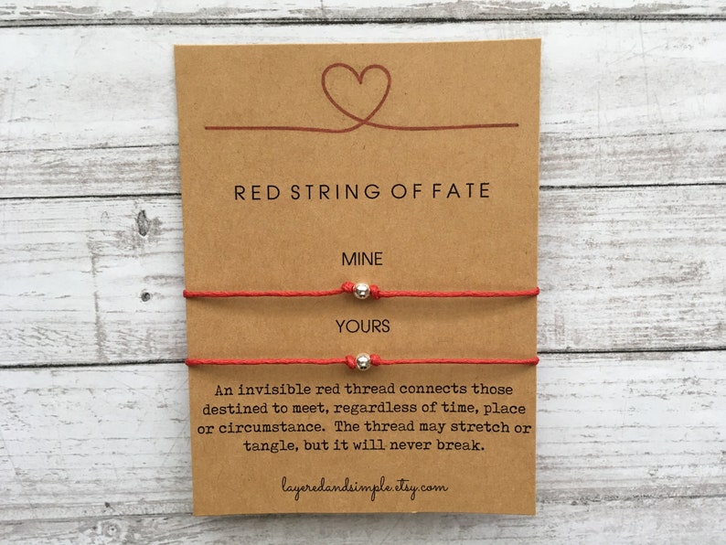 K&ouml;nnte beinhalten: Zwei rote Armb&auml;nder mit silbernen Perlen, eines mit der Aufschrift "MINE" und das andere mit "YOURS". Die Karte lautet "RED STRING OF FATE" und "Ein unsichtbarer roter Faden verbindet diejenigen, die dazu bestimmt sind, sich zu treffen, unabh&auml;ngig von Zeit, Ort oder Umst&auml;nden. Der Faden kann sich dehnen oder verheddern, aber er wird niemals rei&szlig;en." layeredandsimple.etsy.com