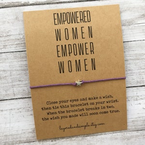May include: A brown card with the text "EMPOWERED WOMEN EMPOWER WOMEN" and a purple string bracelet with a silver star charm. The card also includes instructions for making a wish with the bracelet.