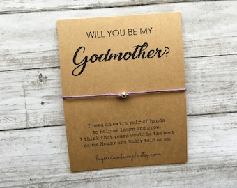 May include: A purple string bracelet with a silver bead, tied around a card that reads "Will you be my Godmother?" with a message about needing an extra pair of hands to help learn and grow. The card also includes the website layeredandsimple.etsy.com.