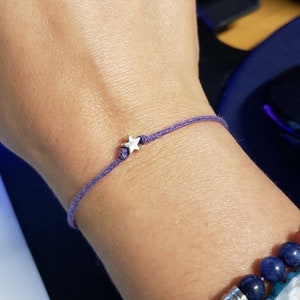 May include: A purple string bracelet with a silver star charm.