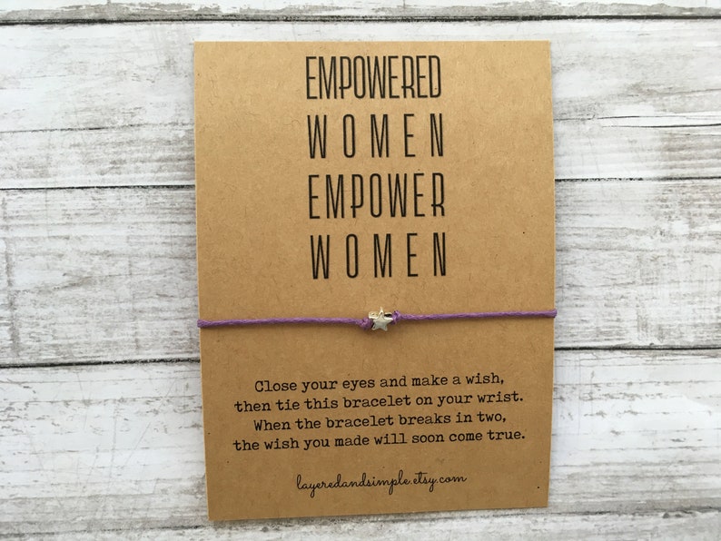 May include: A purple string bracelet with a silver star charm. The card attached to the bracelet reads "EMPOWERED WOMEN EMPOWER WOMEN" and includes instructions for making a wish. The card also includes the website layeredandsimple.etsy.com.