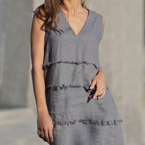 May include: A gray linen dress with a V-neck and a frayed hem.