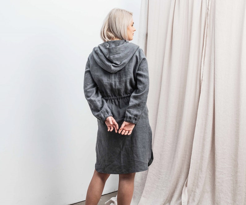 K&ouml;nnte beinhalten: Eine graue, lange, lockere Jacke aus Leinen mit Kapuze und Kordelzug.