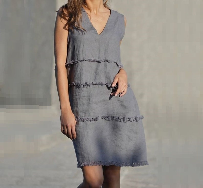 May include: A gray sleeveless linen dress with a V-neck and a tiered, frayed hem.