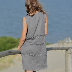 May include: A gray linen dress with a frayed hemline. The dress is sleeveless and has a relaxed fit.