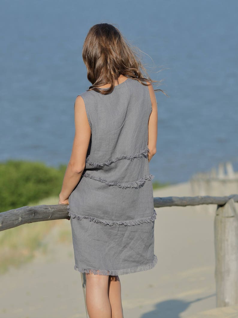 May include: A gray linen dress with a frayed hemline. The dress is sleeveless and has a relaxed fit.