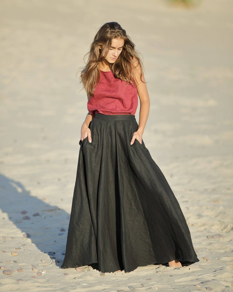 May include: A sleeveless, burgundy-colored top paired with a long, flowing black skirt. The skirt has pockets and a wide, flared design. The outfit is made of a soft, natural fabric, suitable for warm weather.